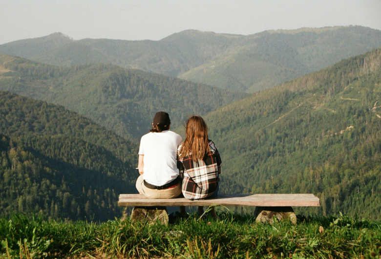 Two people on a bench near hillside trails at Prose at Parkvale apartments in southwest Denver.